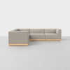A modern, light gray L-shaped sectional sofa with wooden base, set on a light gray floor against a plain white background.