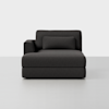 A modern, dark gray upholstered chaise lounge with a left-side armrest and matching rectangular pillow, set against a plain white background.