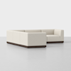 A modern, L-shaped sectional sofa with cream-colored upholstery and a dark wooden base, set against a plain white background.
