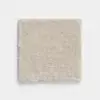 A square sample of light beige carpet with a soft, textured surface, displayed against a plain white background.