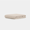 A neatly folded, beige blanket with a quilted pattern, placed on a plain white background.