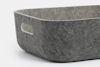 A close-up of a rectangular, grey felt storage basket with rounded edges and an oval cutout handle on the side, set against a plain white background.