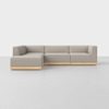 A modern L-shaped sectional sofa with light gray upholstery and a low wooden base, set on a light-colored floor against a plain white background.