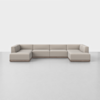 A large, modern sectional sofa in a U-shape with light beige upholstery and low wooden legs, set against a plain white background and gray floor.