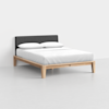 A modern bed with a light wood frame, dark gray upholstered headboard, white bedding, and two white pillows, set against a plain white background.
