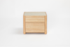 A small, light wood nightstand with two drawers and a flat top, photographed against a plain white background.