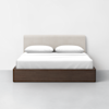 A modern bed with a beige upholstered headboard, white bedding, two pillows, and a dark wooden platform base, set against a plain white wall and gray floor.