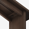 Close-up view of the underside of a dark wooden table or furniture piece, focusing on the corner joint and visible fasteners against a plain white background.