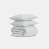 Two light gray pillows are stacked neatly on top of a folded matching duvet, all set against a plain white background.