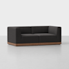 A modern, boxy dark-gray upholstered sofa with deep seats and a low backrest, set on a wooden base, placed on a light gray floor with a plain white background.