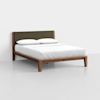 A modern wooden bed frame with angled legs, a dark upholstered headboard, and white bedding with two pillows, placed in a minimalist room with a light gray floor and white walls.