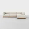 A modern, L-shaped sectional sofa with cream-colored upholstery and a wooden base, set against a plain, light gray background.