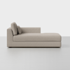 A modern beige chaise lounge with clean lines, low backrest on the left, two square cushions, and minimalist design, set against a plain white background.