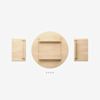 Top-down view of wooden furniture parts: a round tabletop in the center, two rectangular pieces with handles on each side, and four small T-shaped pegs arranged in a row below. All items are on a white background.