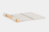 A flat, rectangular, light gray felt desk mat with a wooden cylindrical rod attached along one edge, lying on a white background.