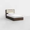A single bed with a dark wooden frame, a beige upholstered headboard, white sheets, and a white pillow, placed in a minimalistic room with white walls and a light gray floor.
