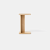 A small, minimalist wooden side table with an I-shaped design, featuring flat rectangular surfaces on the top and bottom and a vertical support in the center, set against a plain white background.