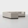 A modern, L-shaped sectional sofa with light beige upholstery and a dark wooden base, set against a plain white background.