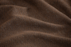 Close-up of textured brown fabric with small, tightly woven fibers and gentle folds creating soft shadows.