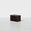 A dark wooden rectangular storage unit with two open shelves, placed on a plain light gray floor against a white background.
