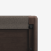 Close-up of the top corner of a wooden bed frame with a grey fabric panel attached, showcasing smooth, rounded edges and dark finish against a plain white background.