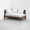 A modern daybed with a dark gray upholstered back, white seat cushion, three white pillows, and a wooden frame is placed against a white corner wall in a minimalistic room with a light gray floor.