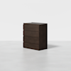 A dark brown wooden dresser with four horizontal drawers, standing on a smooth light gray floor against a plain white background.