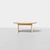 A minimalist, light wood round coffee table with three legs, set against a plain white background.