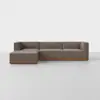 A modern, L-shaped sectional sofa with brown upholstery and a wooden base, set against a plain white background on a light-colored floor.