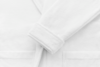 Close-up of a white bathrobe made from soft, textured fabric, showing the sleeve and two front pockets against a plain background.