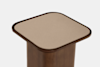 A close-up view of a modern wooden pedestal with a square top featuring rounded corners and a smooth, beige surface. The background is plain white.