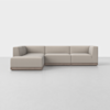 A modern, L-shaped sectional sofa with light beige upholstery and a low wooden base, set against a plain white background on a light gray floor.