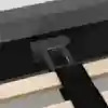 Close-up of a bed frame assembly showing a black metal support bracket attached to a headboard. Wooden slats and a black fabric strap are visible in the foreground.