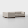 A modern, light beige L-shaped sectional sofa with low back and arms, set on a dark wooden base, positioned on a plain white floor with a white background.