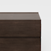 A close-up view of the top section of a dark brown wooden dresser with clean, modern lines, set against a plain white background.