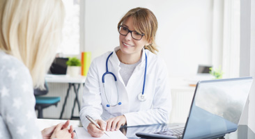 health professional taking notes while talking to a patient