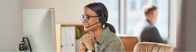 Woman with headset smiling at computer