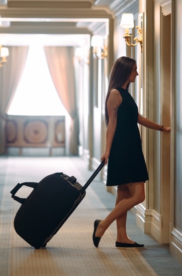 Woman walking into her hotel room with luggage