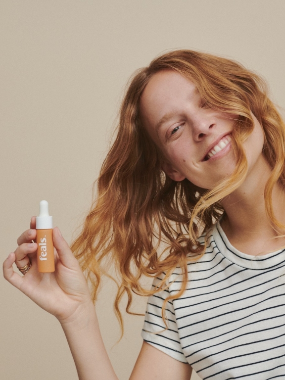 Image - Young woman holding a bottle of Feals CBD oil