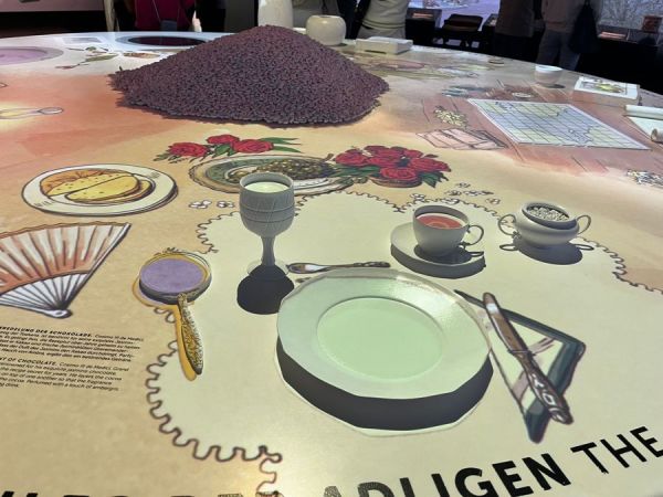 A big table with light projections of chocolate over time and space.