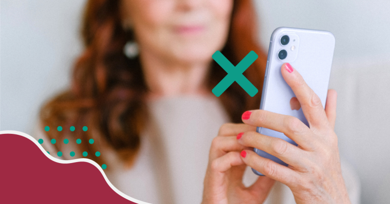På bilden syns en kvinna med rött hår som håller i en vit smartphone. Jämte smartphonen syns ett stort grönt kryss.