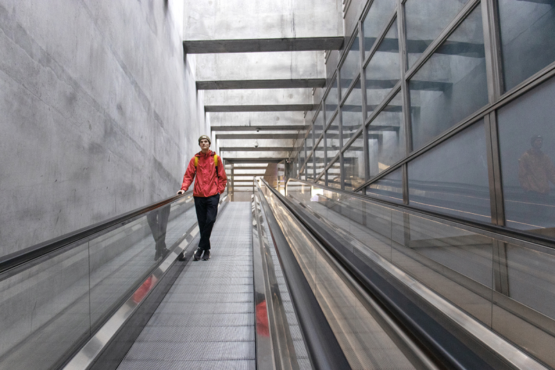 Bild på en person som går på ett rullband i en tågtunnel. Tunneln symboliserar VPN. Personen har en röd jacka och en ryggsäck på sig.
