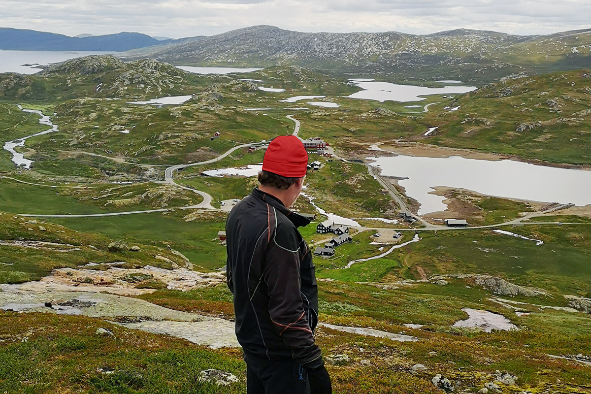 Foto på en man som står på ett berg och kollar ut på ett landskap.
