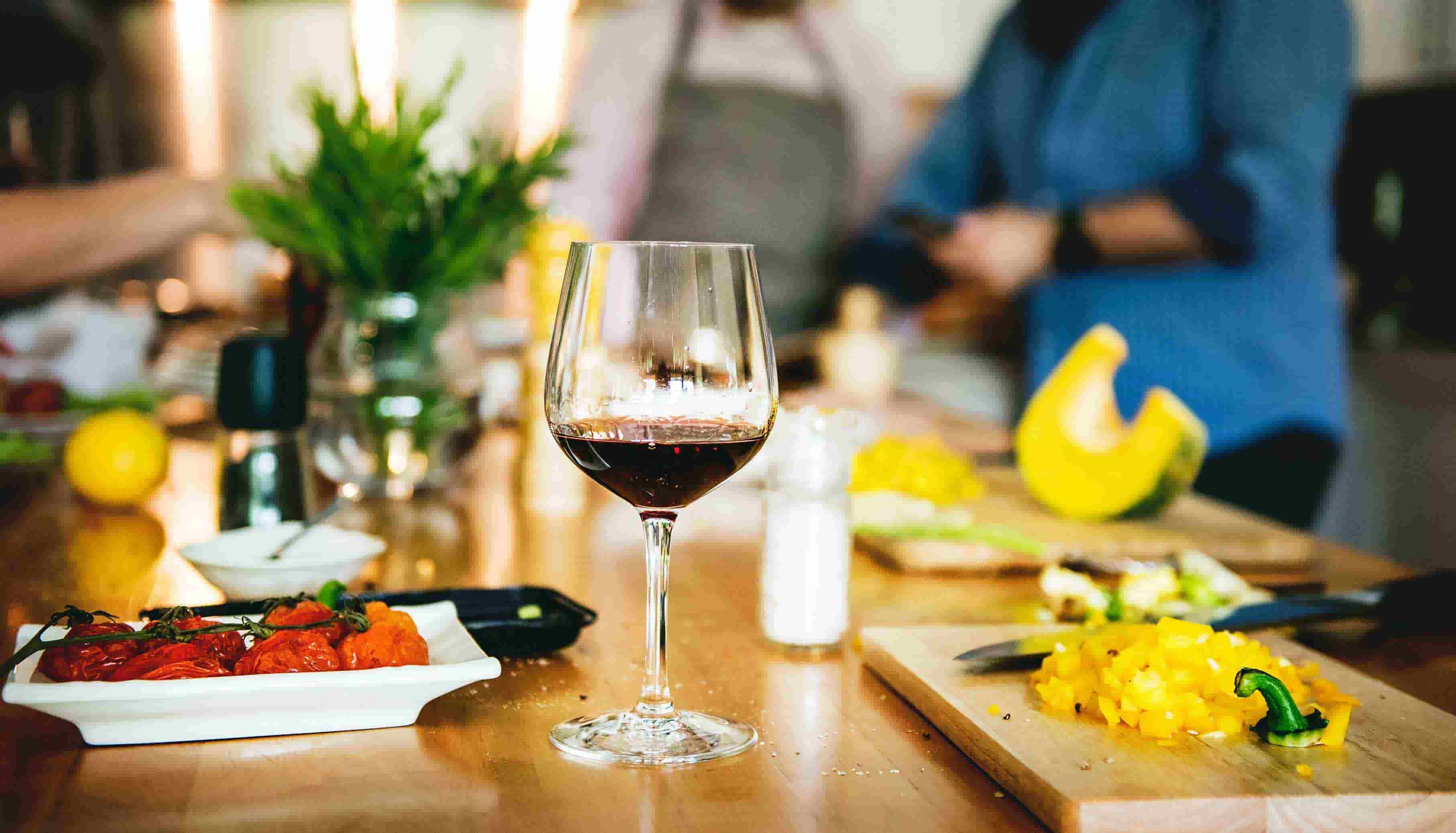 Vegetarian meal being prepared with red wine on table