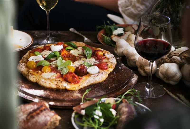 An artisan cheese pizza with a glass of red wine
