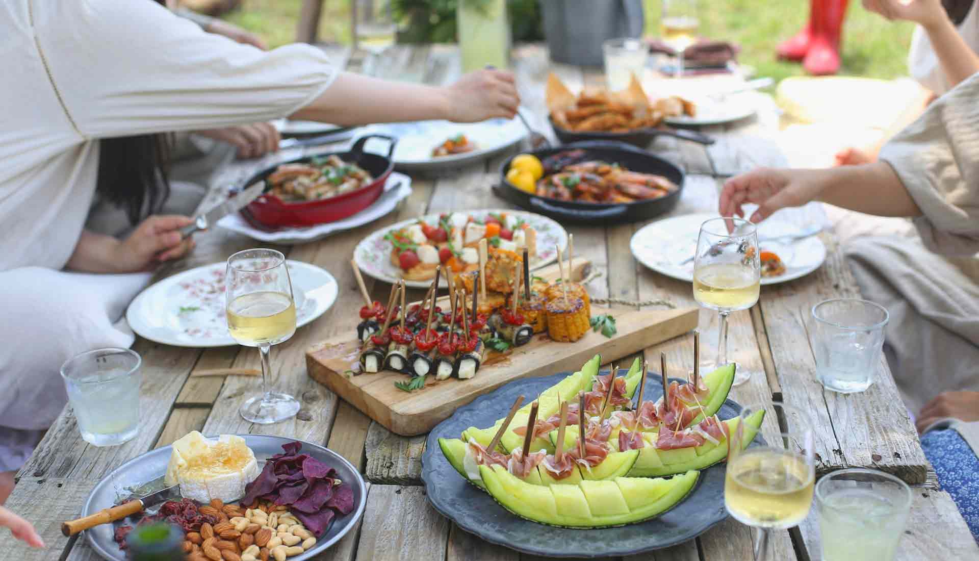 An image of a BBQ with various foods and wine
