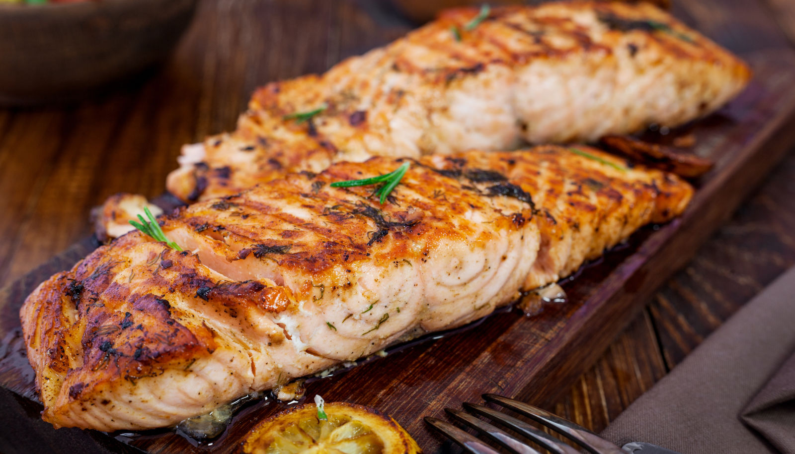 Grilled salmon fillets on a serving board with a slice of lemon - wine with salmon