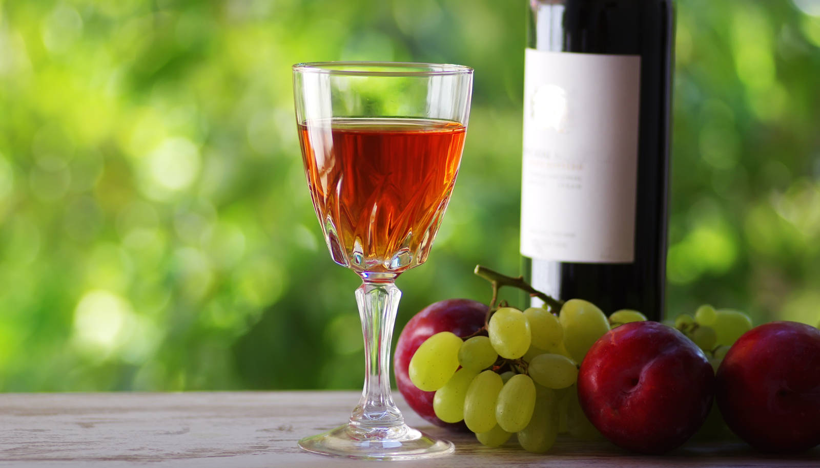 Madeira wine - a glass of Madeira wine with grapes and a wine bottle on a table