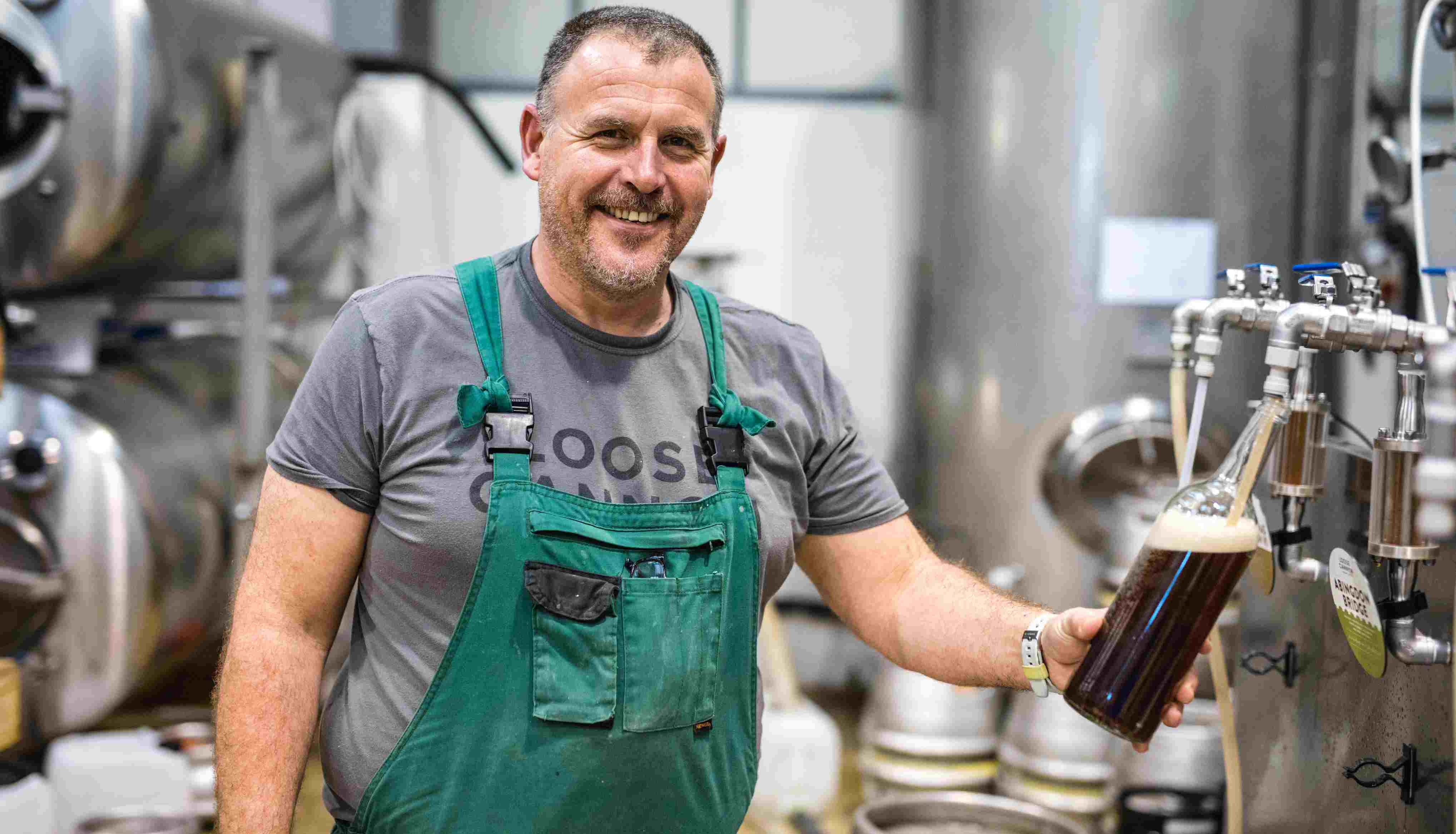Man in apron in brewery pouring a pint of dark beer