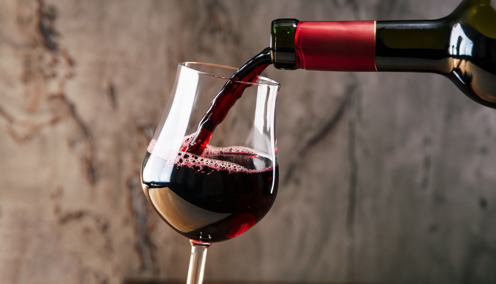 An introductory guide to French Bordeaux wines - a glass of red Bordeaux wine being poured into a glass from a bottle.